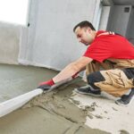 concrete worker levels screed using long piece of wood