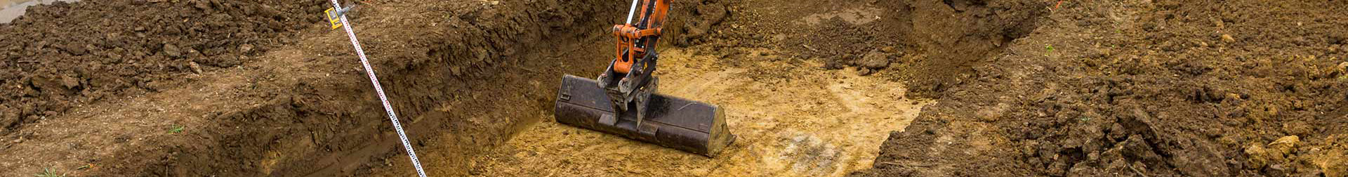 excavator digging the foundation of a pool in a residential dirt covered backyard
